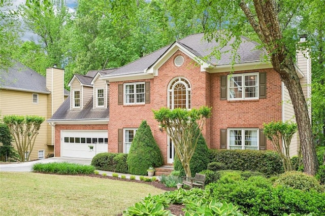 colonial house with a front lawn, roof with shingles, concrete driveway, an attached garage, and brick siding