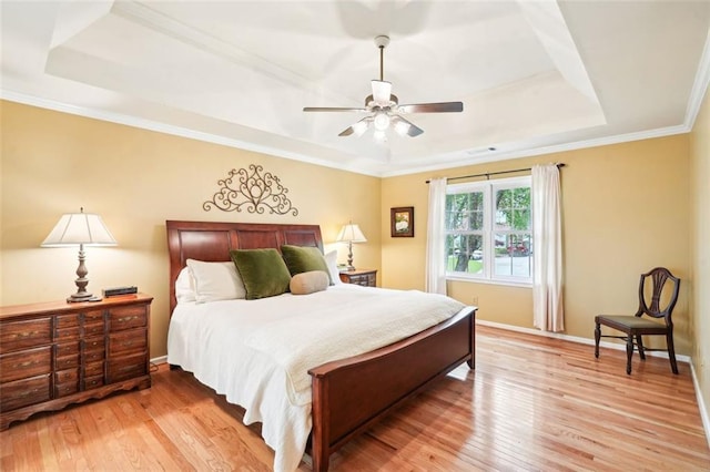 bedroom featuring a raised ceiling, ceiling fan, light wood finished floors, and crown molding