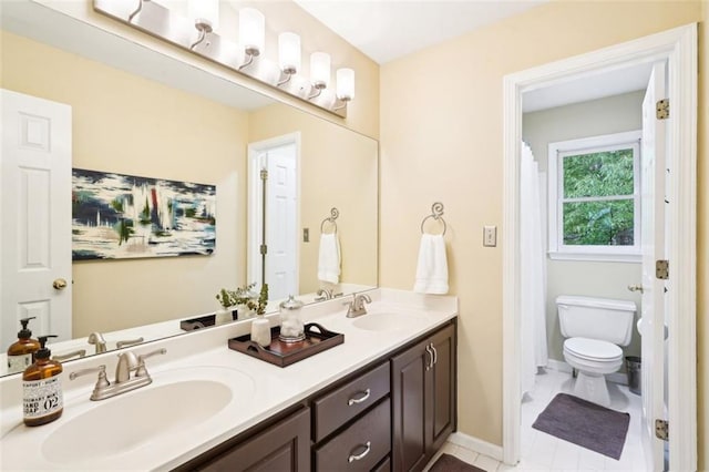 full bathroom featuring toilet, a sink, double vanity, and baseboards