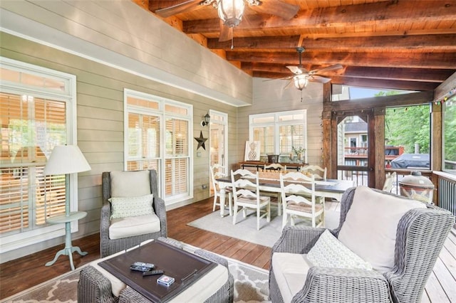 sunroom featuring beam ceiling, outdoor dining area, and ceiling fan