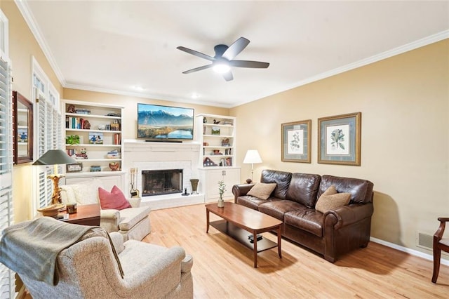 living area featuring ceiling fan, crown molding, a brick fireplace, and light wood finished floors