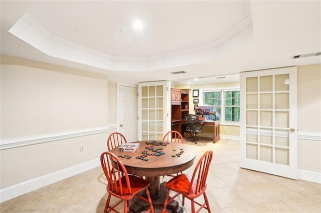 dining space with french doors, a tray ceiling, baseboards, crown molding, and light tile patterned floors