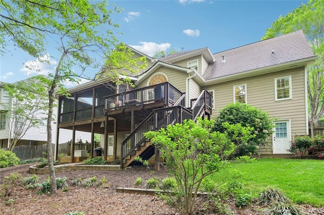 back of house featuring stairway, fence, a yard, a wooden deck, and a sunroom