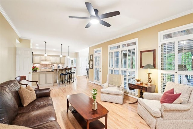 living room featuring ceiling fan, ornamental molding, and light wood-style floors