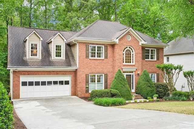 colonial inspired home with driveway, brick siding, roof with shingles, and a garage