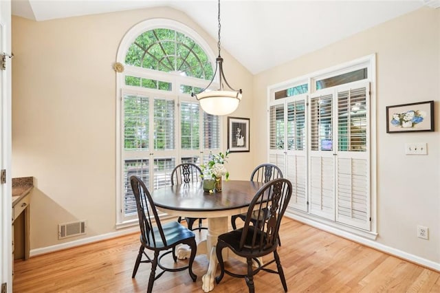 dining space with lofted ceiling, visible vents, baseboards, and light wood-style flooring