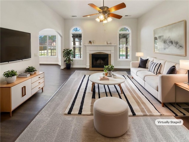 living area featuring visible vents, a fireplace, dark wood finished floors, and a wealth of natural light