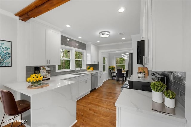 kitchen with appliances with stainless steel finishes, white cabinets, a sink, and a peninsula