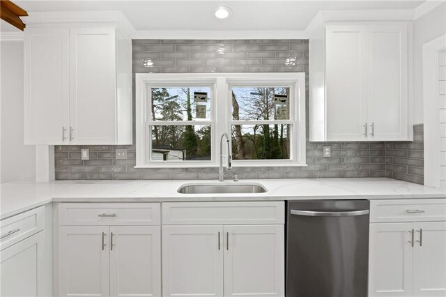 kitchen with light stone counters, stainless steel dishwasher, a sink, and white cabinetry