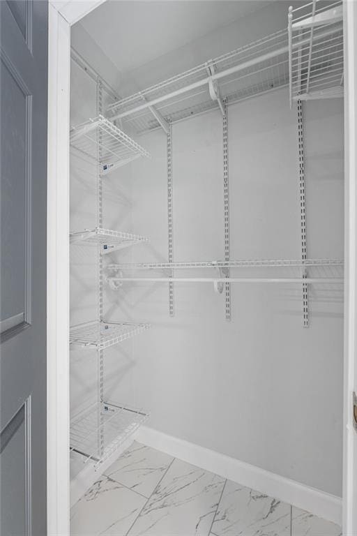 walk in closet featuring marble finish floor