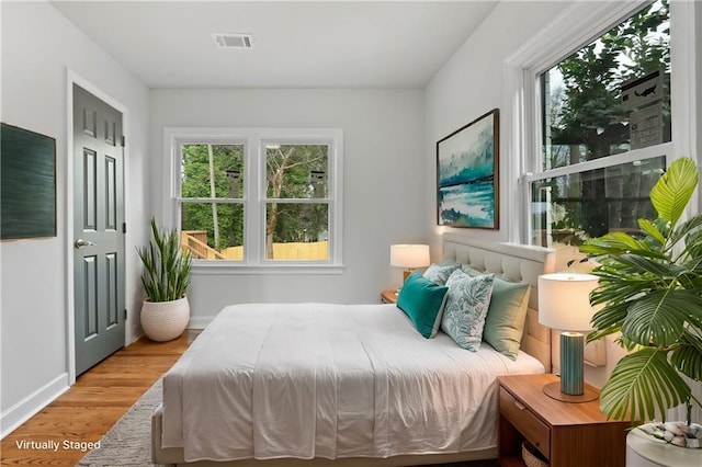 bedroom featuring baseboards, visible vents, and wood finished floors