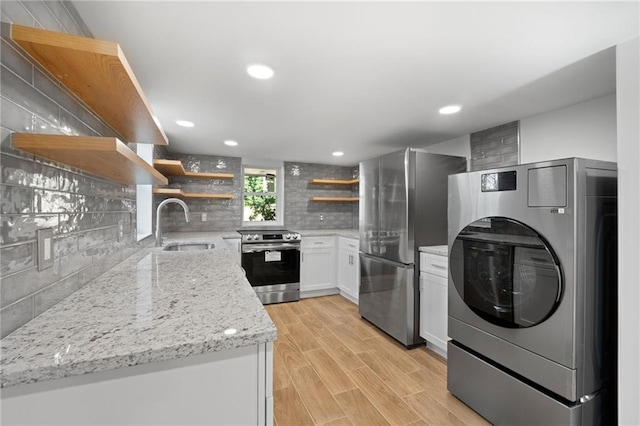 kitchen with decorative backsplash, washer / clothes dryer, appliances with stainless steel finishes, open shelves, and a sink