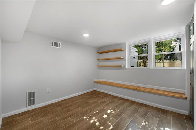 empty room featuring wood tiled floor, visible vents, and baseboards