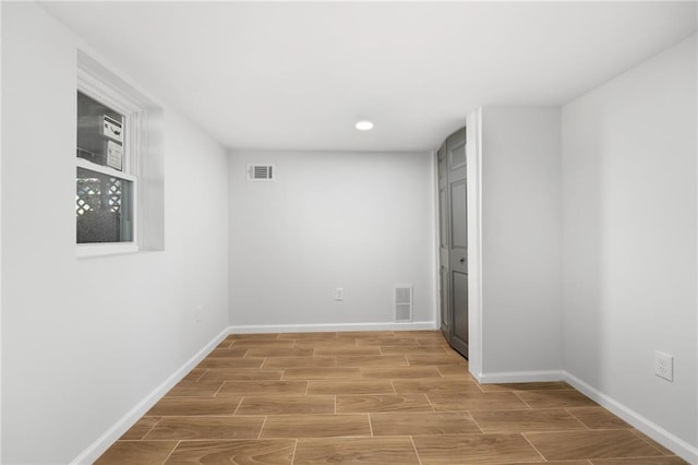 unfurnished room with wood tiled floor, visible vents, and baseboards