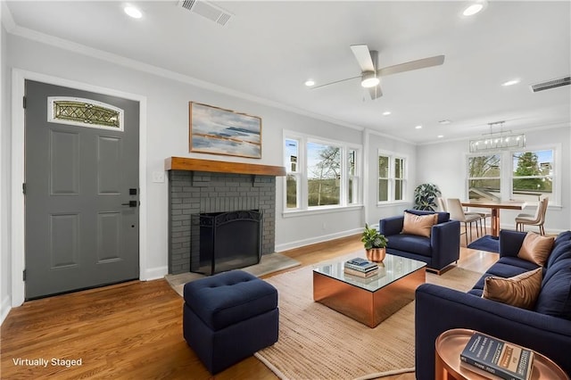 living area featuring a fireplace, visible vents, crown molding, and wood finished floors