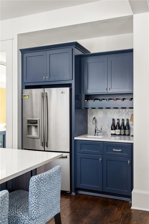 kitchen with blue cabinetry, stainless steel fridge, tasteful backsplash, and dark wood-type flooring