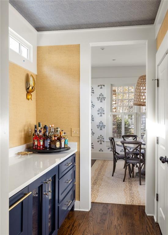 bar with a textured ceiling, blue cabinets, dark wood-type flooring, and a wealth of natural light