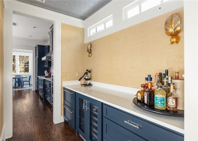 bar with blue cabinetry, a wealth of natural light, and dark hardwood / wood-style flooring