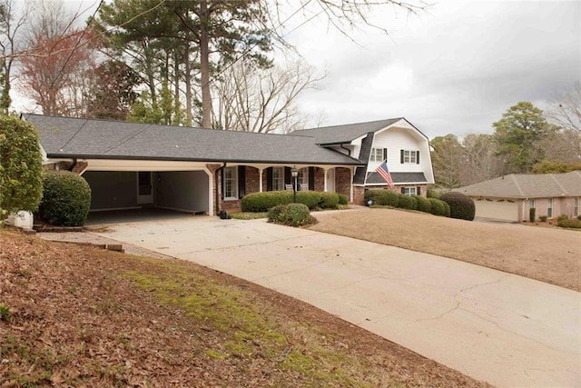 split level home with driveway, roof with shingles, an attached garage, a gambrel roof, and brick siding