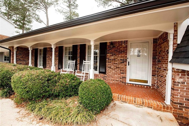 property entrance featuring brick siding and a porch