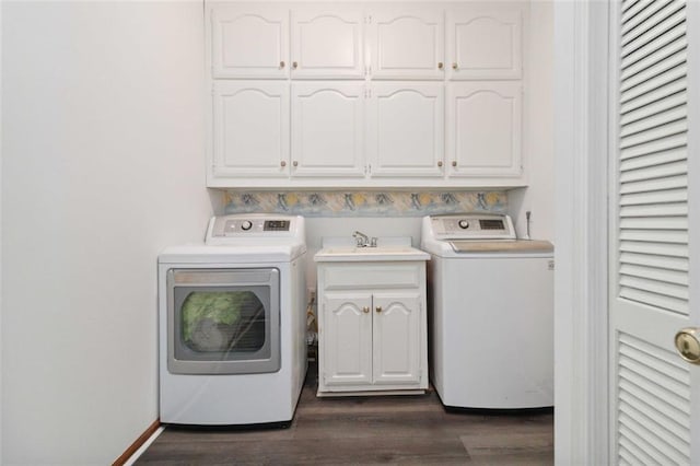 clothes washing area with washer and clothes dryer, cabinets, dark hardwood / wood-style floors, and sink