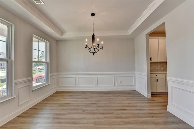 6867 Kate Ln, Flowery Branch, GA 30542 - unfurnished dining area with a tray ceiling, a chandelier, light wood finished floors, a wainscoted wall, and ornamental molding