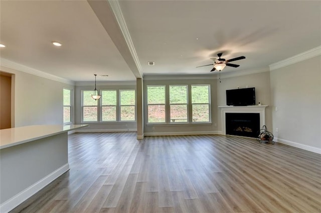 6867 Kate Ln, Flowery Branch, GA 30542 - unfurnished living room featuring plenty of natural light, ornamental molding, a fireplace, light wood-style flooring, and ceiling fan