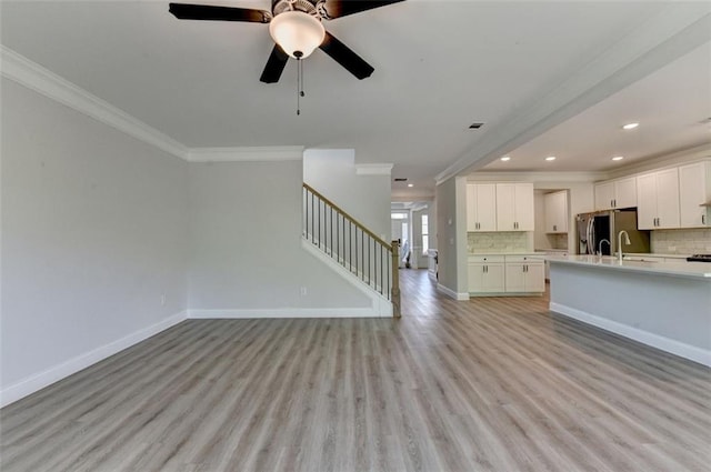 6867 Kate Ln, Flowery Branch, GA 30542 - unfurnished living room featuring ornamental molding, stairs, light wood-style floors, recessed lighting, and a ceiling fan