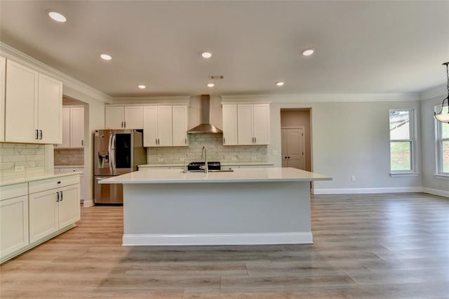 6867 Kate Ln, Flowery Branch, GA 30542 - kitchen featuring wall chimney exhaust hood, stainless steel fridge, crown molding, light countertops, and a kitchen island with sink