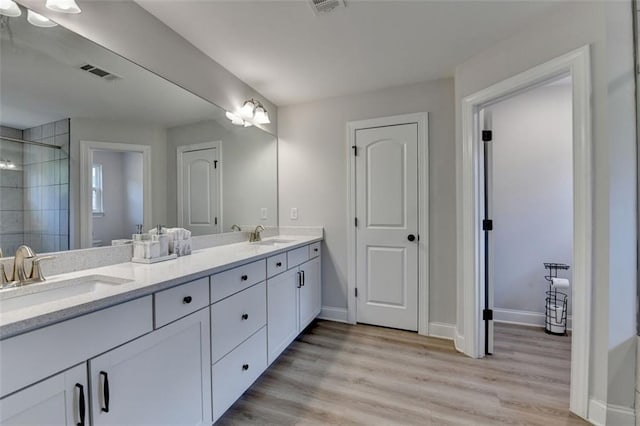 6867 Kate Ln, Flowery Branch, GA 30542 - bathroom with double vanity, a stall shower, and wood finished floors