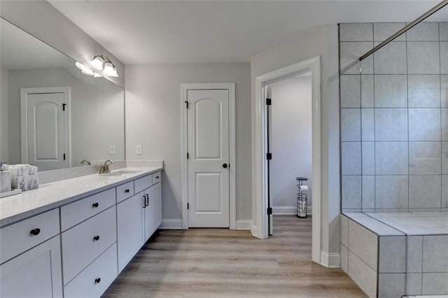 6867 Kate Ln, Flowery Branch, GA 30542 - bathroom featuring vanity, tiled shower, and wood finished floors