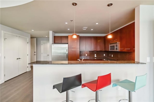 20 10th St NW Unit 704, Atlanta, GA 30309 - kitchen with stainless steel appliances, light wood finished floors, tasteful backsplash, dark stone counters, and a peninsula