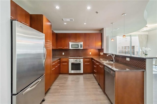 20 10th St NW Unit 704, Atlanta, GA 30309 - kitchen featuring stainless steel appliances, a peninsula, brown cabinets, light wood-style flooring, and decorative backsplash