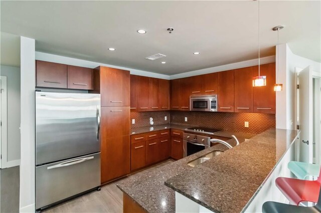 20 10th St NW Unit 704, Atlanta, GA 30309 - kitchen featuring stainless steel appliances, a peninsula, dark stone countertops, backsplash, and pendant lighting