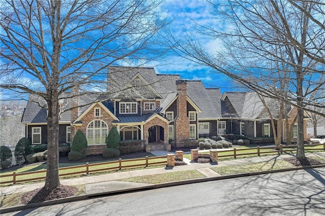 view of front of property with a standing seam roof, a fenced front yard, a chimney, and a front yard