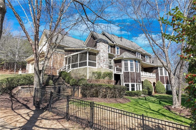 exterior space with a sunroom, a fenced front yard, an attached garage, stairs, and a front lawn