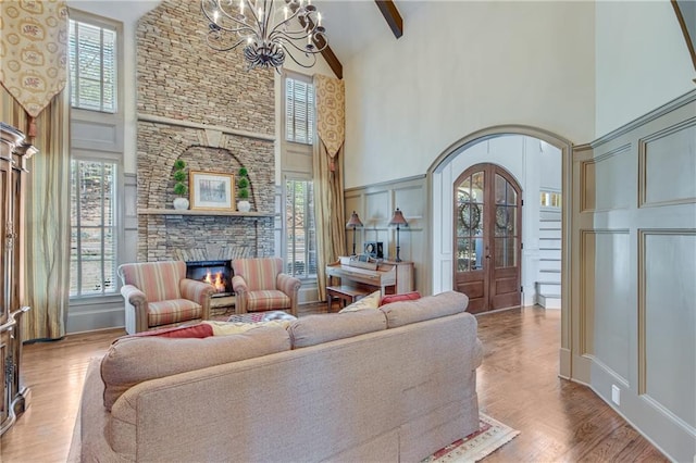 living room featuring arched walkways, a fireplace, a notable chandelier, a decorative wall, and wood finished floors