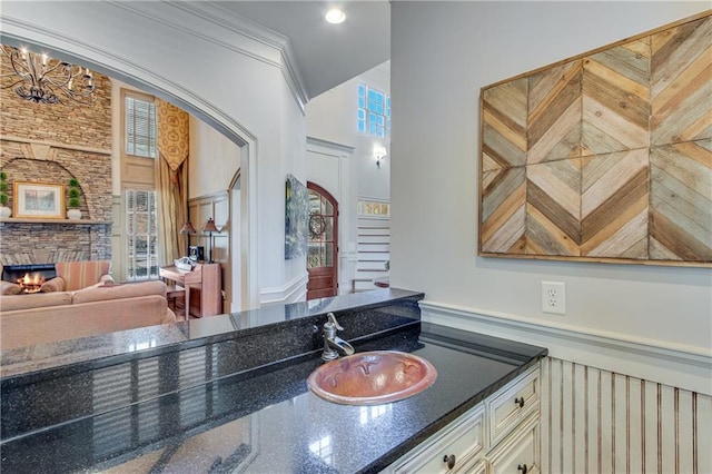 interior space featuring dark stone counters, a stone fireplace, cream cabinets, and a sink