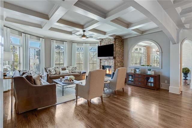 sunroom with beam ceiling, coffered ceiling, a fireplace, and ceiling fan