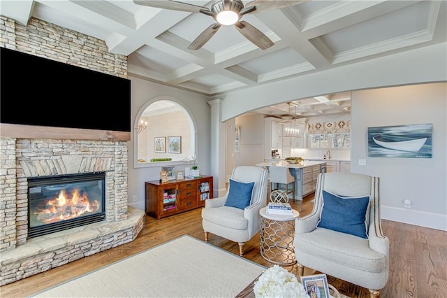 living area with beamed ceiling, a fireplace, coffered ceiling, and wood finished floors