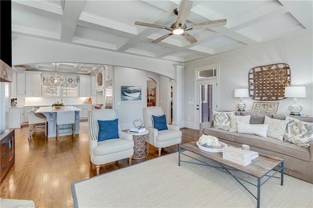 living area with arched walkways, ceiling fan, coffered ceiling, beam ceiling, and light wood finished floors