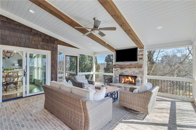 sunroom / solarium featuring vaulted ceiling with beams, ceiling fan, and an outdoor stone fireplace