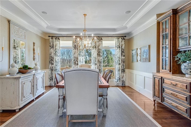 dining area featuring a chandelier, a tray ceiling, wainscoting, and dark wood finished floors