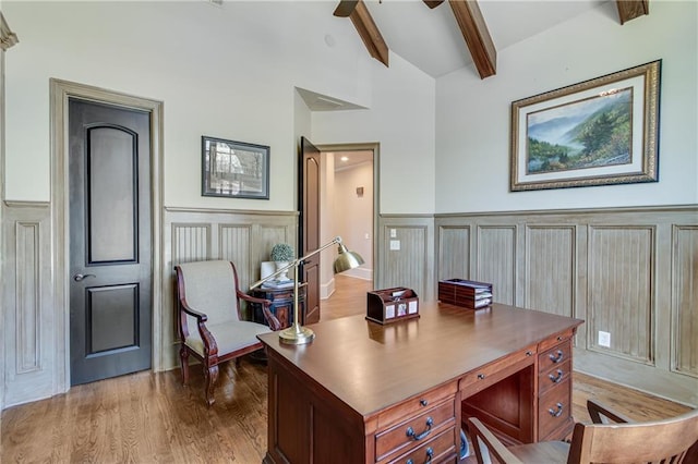 office space with vaulted ceiling with beams, ceiling fan, a decorative wall, wood finished floors, and wainscoting