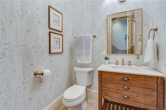 bathroom with vanity, toilet, and wallpapered walls