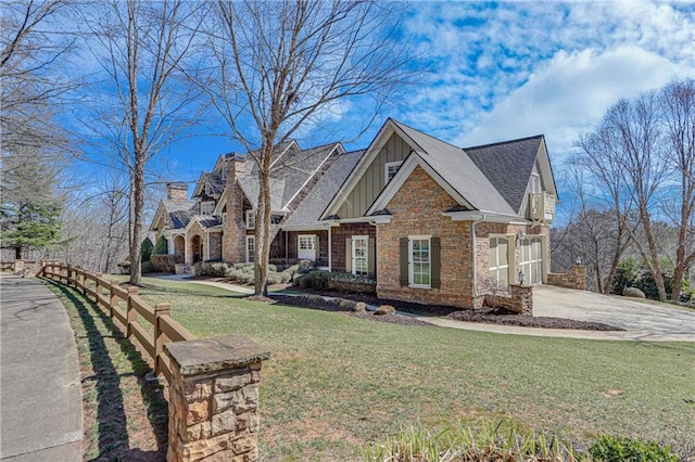 craftsman house with driveway, a garage, a front yard, board and batten siding, and brick siding