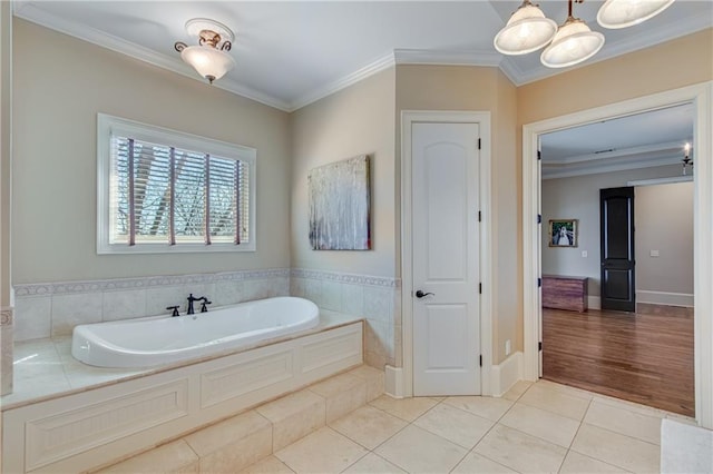 full bath featuring ornamental molding, tile patterned flooring, a garden tub, and baseboards