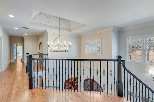 hallway with visible vents, ornamental molding, an upstairs landing, wood finished floors, and a chandelier