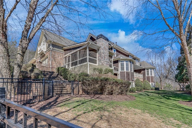 view of home's exterior featuring a yard, stairway, fence, and a sunroom