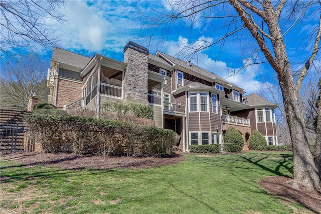 rear view of property with a lawn, a chimney, and a sunroom